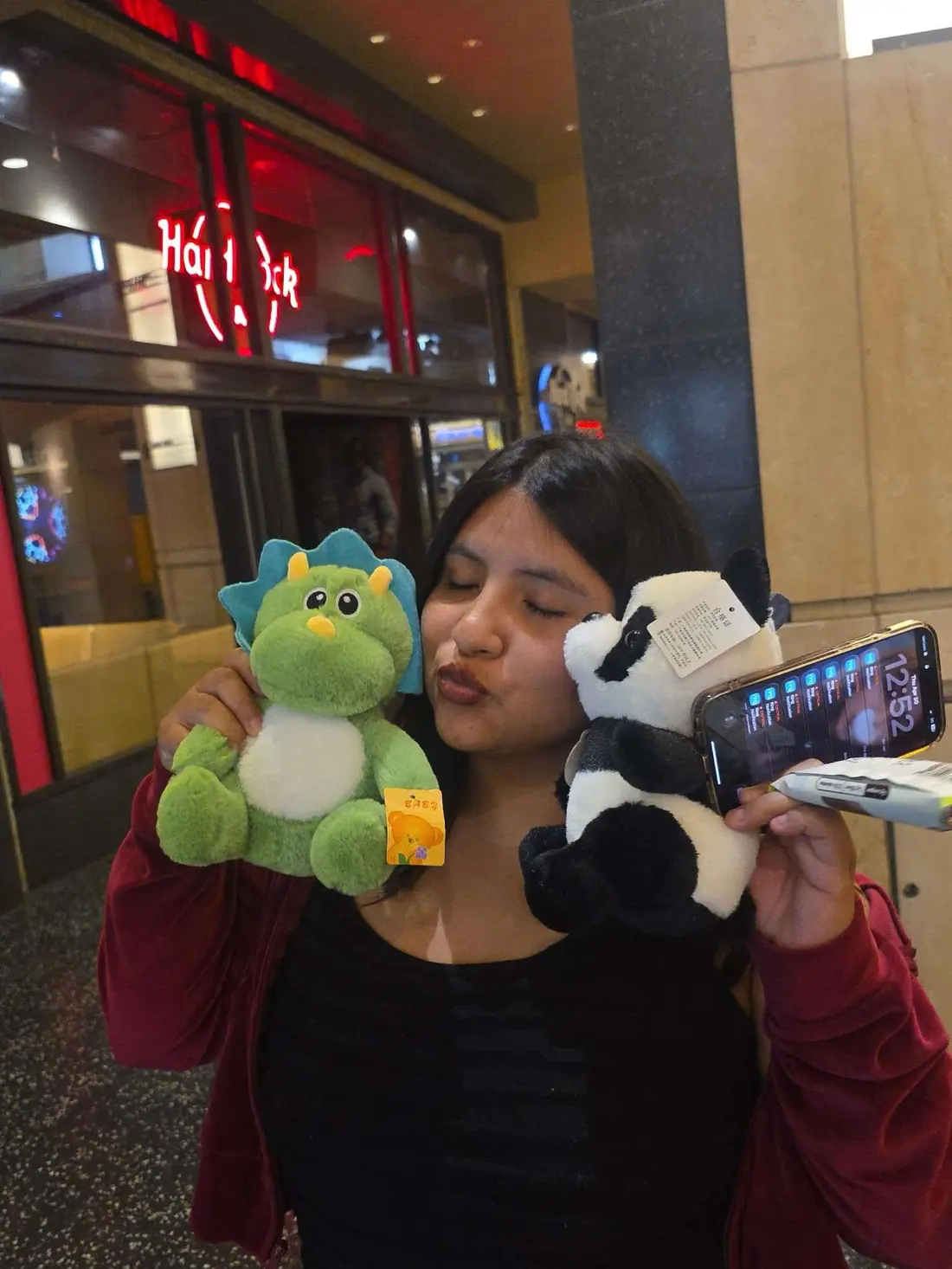 A woman holding the green dinosaur and panda plushies she just won