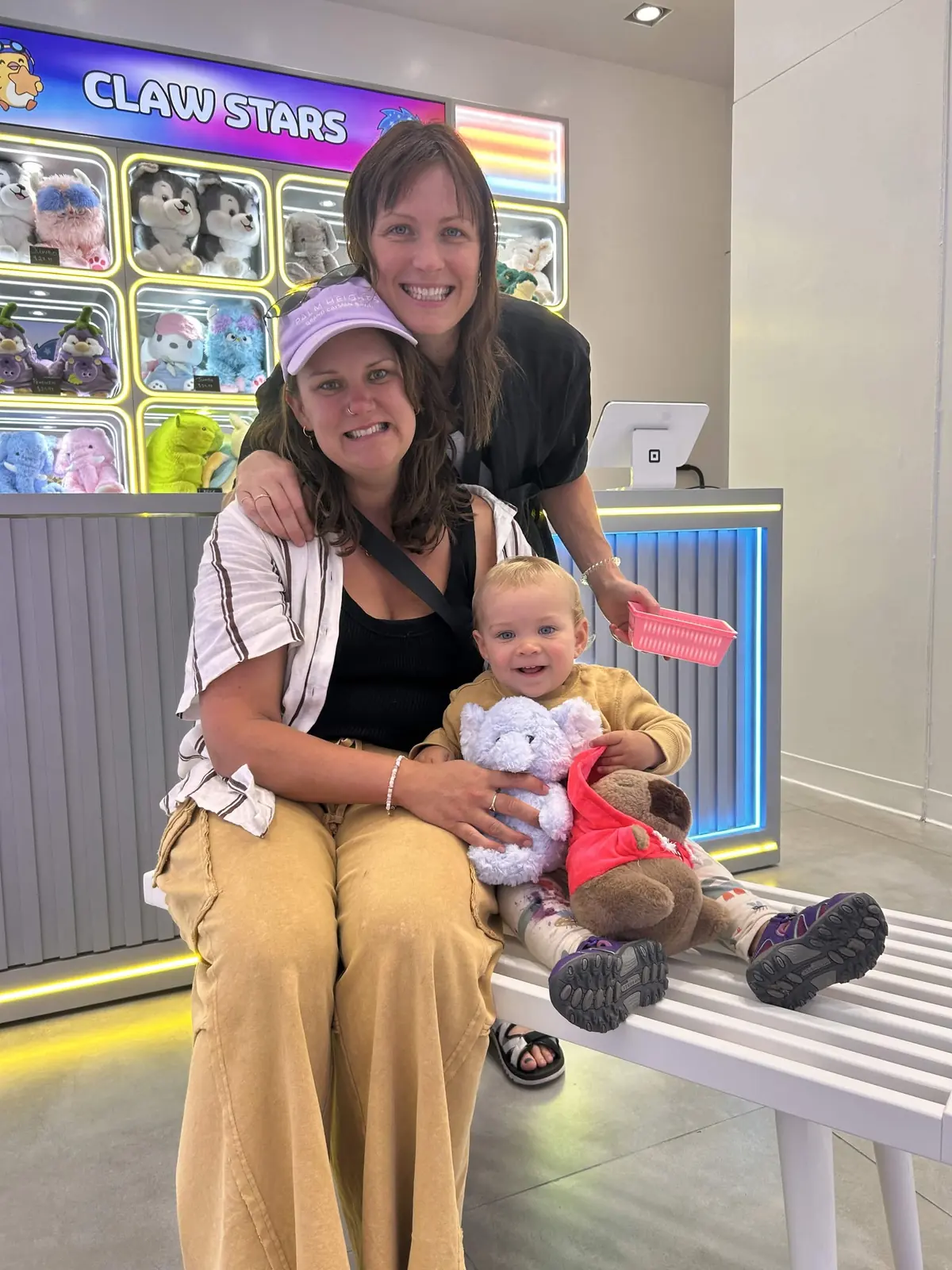 A mother holding her baby beside a claw machine, both smiling